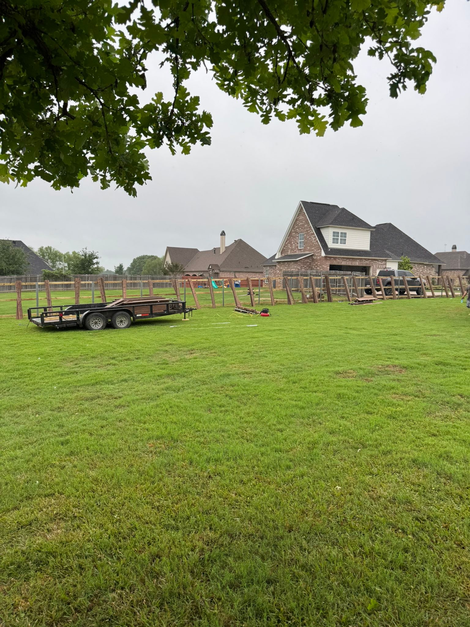 Fence installation in progress with equipment trailer on site