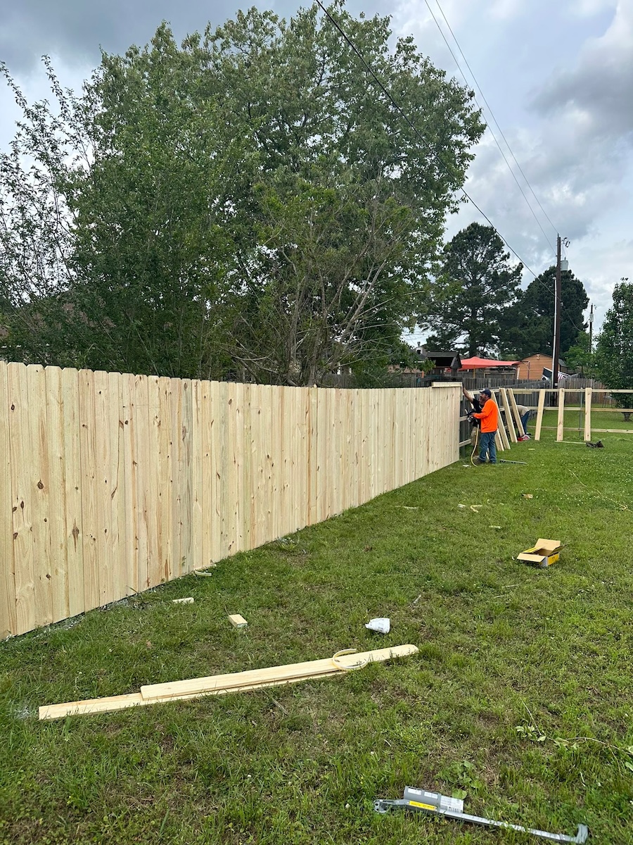 Straight Line Fencing crew installing a wood privacy fence panel